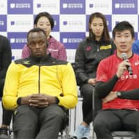 Yoshihide Kiryu (right) speaks at a news conference on Saturday at the new National Stadium. Usain Bolt (center) and other high-profile athletes and entertainers took part in events to welcome the public to the stadium for the first time. | KYODO