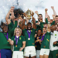 South Africa captain Siya Kolisi lifts the Webb Ellis Cup as his team celebrates winning the Rugby World Cup final against England on Nov. 2. | AFP-JIJI