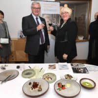 Danish Ambassador Peter Taksoe-Jensen (left) stands next to Minister-Counsellor Lene Molsted Jensen in front of a series of tableware created by 17 professional Danish craftspeople and designers during  the Designing for Health 2019 event at the Danish Embassy in Tokyo on Nov. 29. | YOSHIAKI MIURA