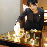 A shop clerk shows off a Jinsei Game (The Game of Life) set made of pure gold Thursday at a Tanaka Kikinzoku Kogyo K.K. outlet in the city of Fukuoka. The traditional board game, similar to Snakes and Ladders and themed on the ups and downs of life, uses some 12.4 kilograms of pure gold and is worth some &#165;150 million. The jeweler made the set in collaboration with toy-maker Tomy Co., which sells the original Jinsei Game. | KYODO