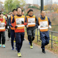 About 50 Metropolitan Police Department officers jog around the Imperial Palace in Tokyo\'s Chiyoda Ward on Friday wearing clothing with messages saying \"No Drones!\" as part of efforts to raise public awareness of the prohibition on flying unmanned aircraft near the palace, airports and crowded residential areas. | KYODO