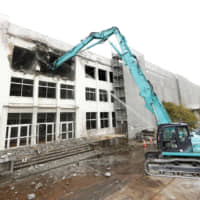 Part of a building that housed Kadonowaki Elementary School in Ishinomaki, Miyagi Prefecture, is dismantled on Monday. The school was flooded by a surge of seawater 1.8 meters deep during the March 2011 tsunami. The central part will be preserved for public viewing until March 2022. All of the students who were on campus at the time survived. | KYODO