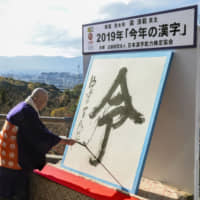 Seihan Mori, chief priest of Kiyomizu Temple in Kyoto, writes \"rei,\" the kanji character of the year, in traditional Japanese calligraphic style on a large piece of washi paper. The character \"rei\" &#8212; used in the Reiwa era name, which has been translated to mean \"beautiful harmony\" &#8212; was chosen in a nationwide poll. | KYODO