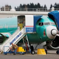 An employee works near a Boeing 737 Max aircraft at Boeing\'s 737 Max production facility in Renton, Washington, in December. | REUTERS