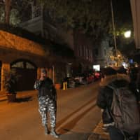 A member of the Lebanese security forces stands guard as journalists wait near the underground parking of a house said to belong to former Nissan chief Carlos Ghosn in a wealthy neighborhood of Beirut on Monday. | AFP-JIJI