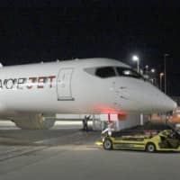 A new prototype of Mitsubishi Aircraft Corp.\'s small SpaceJet passenger aircraft is towed from an assembly plant to the adjacent Nagoya Airport in Toyoyama, Aichi Prefecture, on Jan. 6. | KYODO
