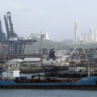 A cargo ship finishes its transit through the Panama Canal on the Pacific side, seen from Panama City Monday. The Panama Canal Authority announced it will start charging customers for their use of fresh water during their transit thought the canal, amid a decrease in rainfall that has lowered lake levels that supply water for human consumption and maritime operations. | AP