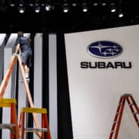 A worker cleans a wall at Subaru Corp.\'s booth during preparations for the Los Angeles Auto Show in 2017. | BLOOMBERG