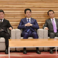 Flanked by Foreign Minister Toshimitsu Motegi (left) and Finance Minister Taro Aso, Prime Minister Shinzo Abe attends a Cabinet meeting Friday to approve bills on a tax reform package for fiscal 2020. | KYODO