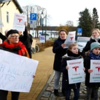 Demonstrators hold pro-Tesla posters during an action to support plans by U.S. electric vehicle pioneer Tesla to build its first European factory and design center in Gruenheide near Berlin Saturday. | REUTERS