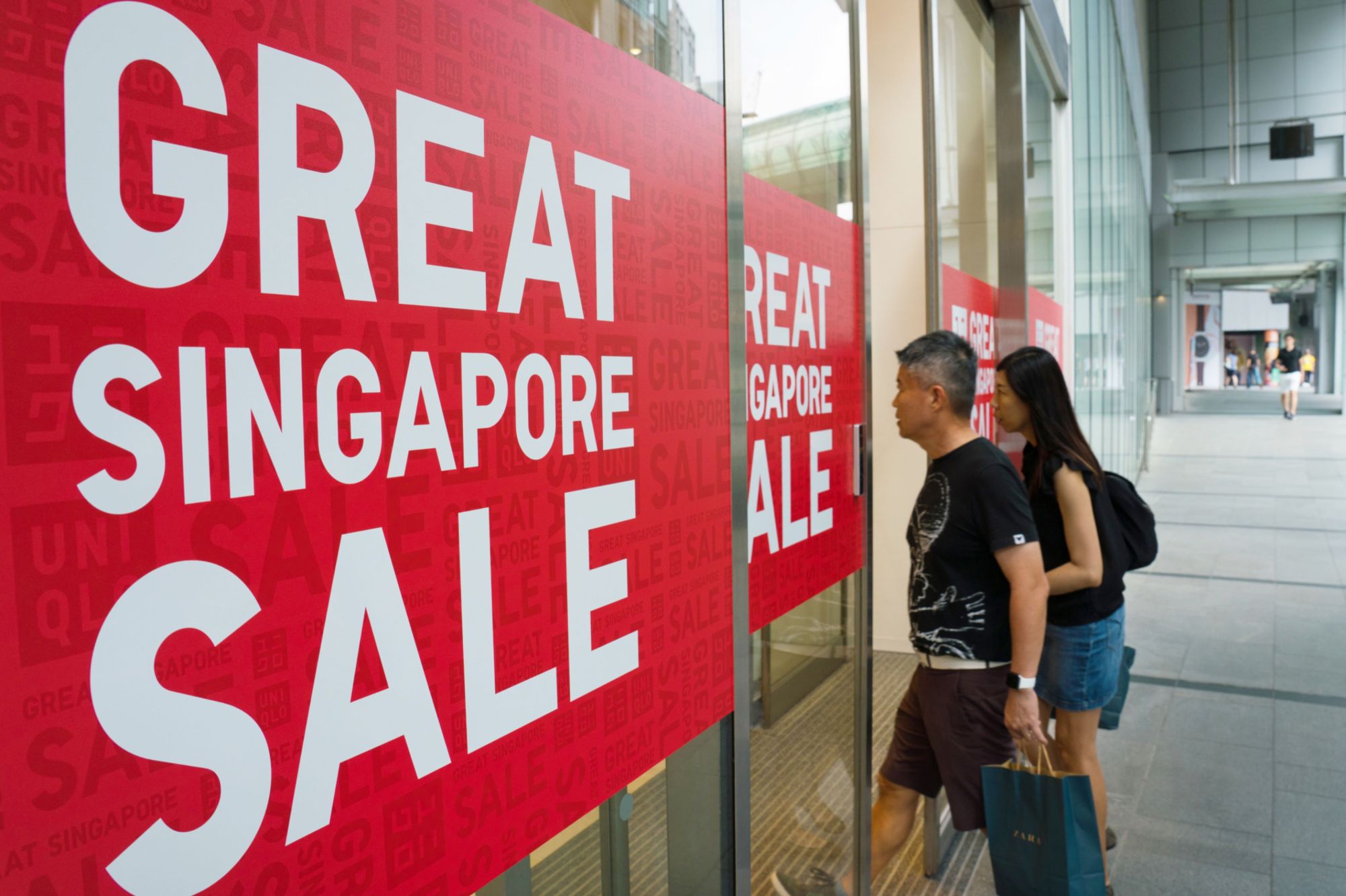 Sale posters are displayed at the entrance to a Uniqlo store in the Orchard Central shopping mall in Singapore. | BLOOMBERG