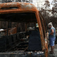 Alisha Stoneham returns to her property, where she and her partner were nearly caught in the flames before narrowly escaping, following the recent bushfires in Conjola Park, New South Wales, Australia, Tuesday. | REUTERS