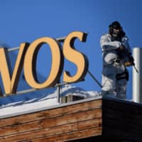 An armed policeman stands on the rooftop of a hotel near the Congress Centre during the annual meeting of the World Economic Forum in Davos, Switzerland, on Monday. From oil demand, car production and the proportion of young people as a share of the population, politicians, investors and executives at the Alpine resort are busy debating whether we are witnessing peaks in key drivers of the world economy. | AFP-JIJI