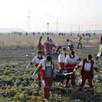 Rescue workers recover the bodies of victims of a Ukrainian plane crash in Shahedshahr, southwest of Tehran, Wednesday. | AP