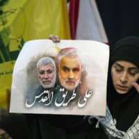 A supporter of Hezbollah leader Sayyed Hassan Nasrallah wears the words \"powerful revenge\" on her hand, ahead of the leader\'s televised speech in a southern suburb of Beirut Sunday following the U.S. airstrike in Iraq that killed Iranian Revolutionary Guard Gen. Qassem Soleimani. The placard in her other hand depicts Soleimaini and Iraq\'s Popular Mobilization forces commander, Abu Mahdi al-Muhandis, who was also killed in the strike. Arabic on placard reads: \"On the road to Jerusalem.\" | AP