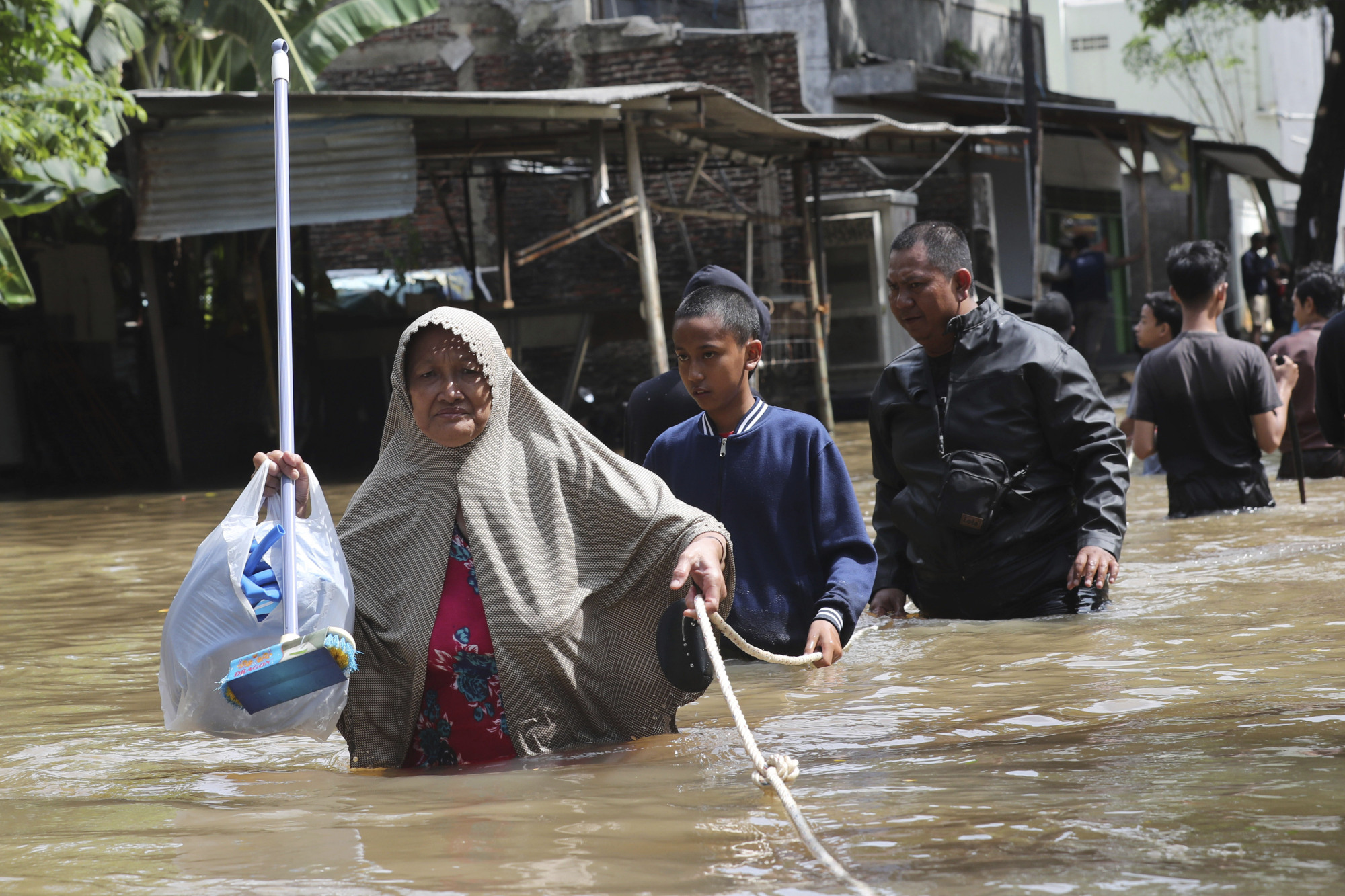 Residents of Tanggerang wade through their flooded neighborhood outside Jakarta on Thursday. | AP