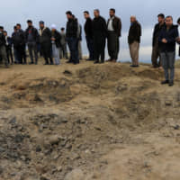 Iraqis look at a crater from a missile launched by Iran against U.S.-led forces on the outskirts of Duhok on Wednesday. | REUTERS