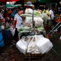 Vendors sell vegetables from plastic bags at a market in Bangkok in June. | REUTERS