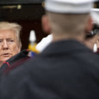 President Donald Trump, accompanied by first lady Melania Trump, stand in the rain as they wait to welcome Greek Prime Minister Kyriakos Mitsotakis and his wife, Mareva Grabowski-Mitsotakis, before they arrive on the South Lawn of the White House Tuesday in Washington. | AP