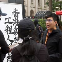 Chris Ngai, chairman of the Hong Kong Construction and Engineering Employees General Union, talks to people near his union\'s recruitment booth set up along the route of the New Year\'s anti-government march in Hong Kong on Jan. 1. | REUTERS