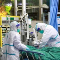 Medical staff treat a patient with pneumonia caused by the new coronavirus at the Zhongnan Hospital of Wuhan University on Tuesday. | CHINA DAILY / VIA REUTERS