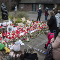 A women lights a candle at the main entrance of the zoo in Krefeld, Germany, on Thursday. | AP