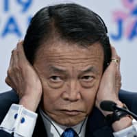Deputy Prime Minister Taro Aso, who serves concurrently as finance minister, listens to a question during a news conference in Washington last October. | BLOOMBERG