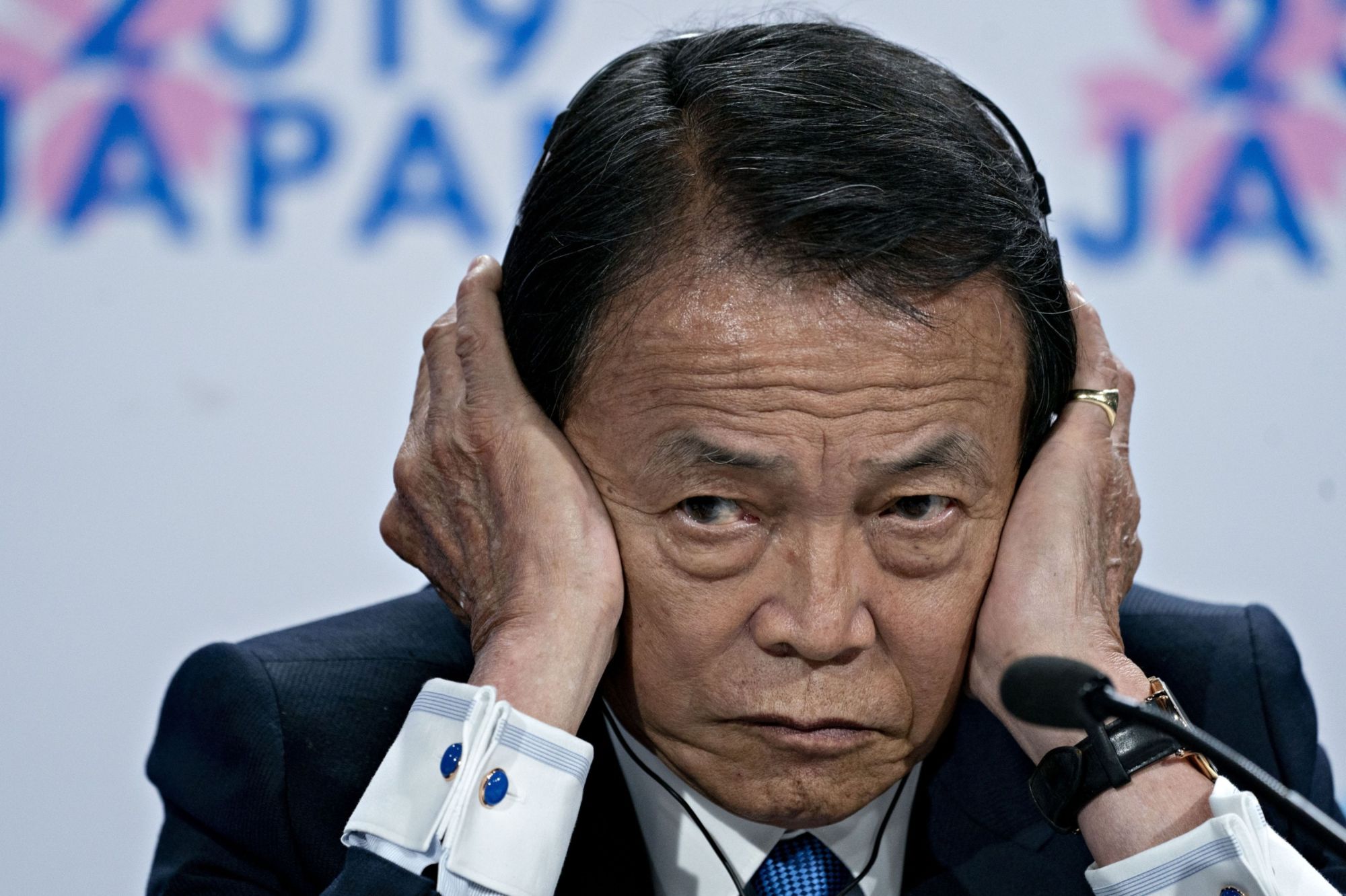 Deputy Prime Minister Taro Aso, who serves concurrently as finance minister, listens to a question during a news conference in Washington last October. | BLOOMBERG