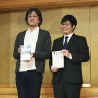 Makoto Furukawa (right), winner of the Akutagawa Prize, and Soichi Kawagoe, winner of the Naoki Prize, hold copies of their respective books at a Tokyo hotel on Wednesday. | ?¯