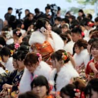 Women draped in traditional kimono gather for their Coming-of-Age Day ceremony at Tokyo Disneyland in Urayasu, Chiba Prefecture, on Monday. | AFP-JIJI