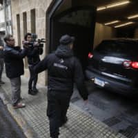 Reporters and a private security guard stand outside the parking entrance of a house said to belong to former Nissan chief Carlos Ghosn in a wealthy neighborhood of Beirut Tuesday. Ghosn will give a hotly awaited press conference in Lebanon on Wednesday, his spokesman said, offering clarity on his recent flight from Japan. | AFP-JIJI