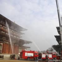 During a drill, firefighters spray water toward the main building of Yakushiji Temple in the city of Nara on Monday. The temple is a World Heritage-listed site.  | KYODO