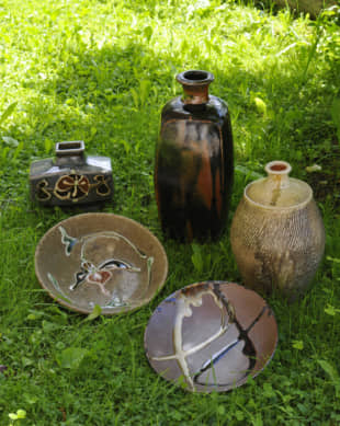 Modern masters: Works by leading 20th-century mingei master potters are arranged on the grass in Jeffrey Montgomery's garden. Clockwise from the tall bottle by Bernard Leach (photo center back) are a bottle made by Tatsuzo Shimaoka; a shallow dish with an abstract 'two fishes' design by Shoji Hamada (1894-1978); and a dish and bottle with raised floral designs by Kanjiro Kawai. | HIROSHI ABE