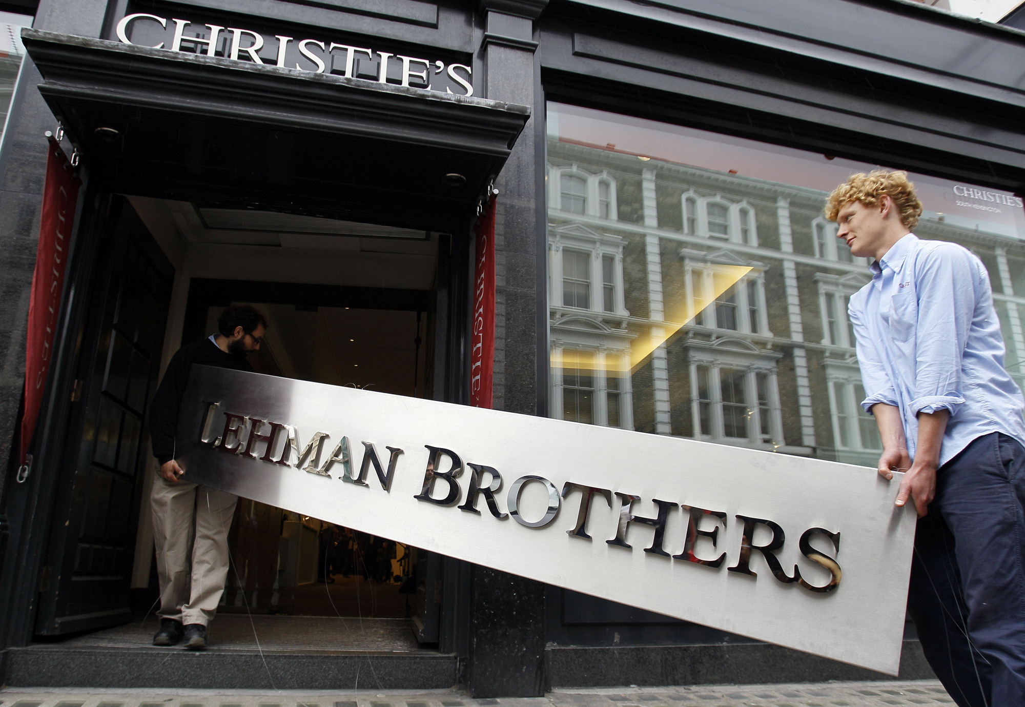 A Lehman Brothers corporate sign is carried into an auction house in London in September 2010. The 2008 bankruptcy of the global financial services firm gave birth to the roaring and tumultuous decade that followed. | ASSOCIATED PRESS