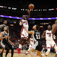 The Heat\'s Kendrick Nunn leaps to make a pass over the Spurs\' Bryn Forbes in the second half on Wednesday in Miami. | AP
