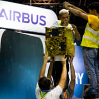 Workers handle a part of a display at the Airbus SE booth during a media preview day at the Singapore Airshow held at the Changi Exhibition Centre in Singapore on Sunday. | BLOOMBERG