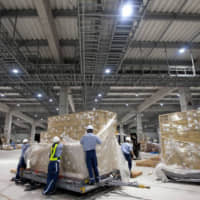 Workers sort packages at an air cargo terminal at Naha Airport in Okinawa Prefecture. | BLOOMBERG