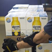 A worker carries packages of Corona beer, a brand owned by Constellation Brands. | BLOOMBERG