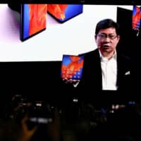 Richard Yu, CEO of Huawei Technologies Consumer Business Group, holds a Huawei Mate Xs foldable smartphone as he talks to the audience on a big screen during a Huawei stream product launch event in Barcelona, Spain, Monday. | REUTERS