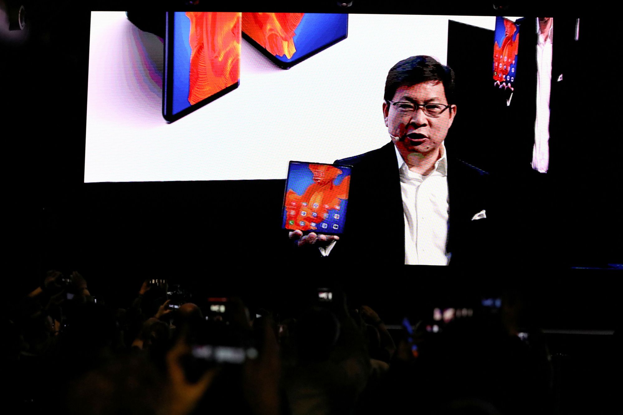 Richard Yu, CEO of Huawei Technologies Consumer Business Group, holds a Huawei Mate Xs foldable smartphone as he talks to the audience on a big screen during a Huawei stream product launch event in Barcelona, Spain, Monday. | REUTERS