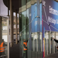Workers clean the windows in one of the entrances at the Mobile World Congress 2020 venue in Barcelona, Spain, Tuesday. Organizers of the world\'s biggest mobile technology fair are pulling the plug over worries about the viral outbreak from China. | AP