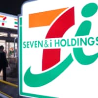 A customer leaves a 7-Eleven convenience store, operated by Seven &amp; i Holdings Co., in Tokyo in January. | BLOOMBERG