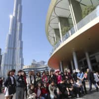 Chinese tourists pose for a photo under the world\'s tallest tower, Burj Khalifa, in Dubai, United Arab Emirates, Jan. 30. The World Health Organization declared the outbreak sparked by a new virus in China that has been exported to more than a dozen countries as a global emergency after the number of cases spiked tenfold in a week. | AP
