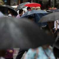 People shelter under a jumble of umbrellas Friday as rain falls amid a severe weather warning by the Bureau of Meteorology for the coast of New South Wales state. The rain comes as a slight relief for some areas dealing with wildfires that have devastated large swathes of land across the state over the past several months. | AP
