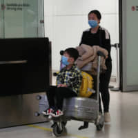 Travelers, wearing masks as a precautionary measure to avoid contracting coronavirus, are seen at Guarulhos International Airport in Guarulhos, Sao Paulo state, Brazil, Monday. | REUTERS