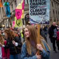 Climate activists march during a protest organized by the climate change action group Extinction Rebellion in London on Saturday. The youth-led Teach the Future campaign network in Britain is demanding a new U.K. law that would instruct all schools to teach climate issues. | AFP-JIJI