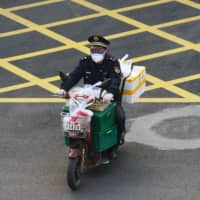 A man wearing a face mask rides a bike filled with food supplies in Wuhan, the epicenter of the novel coronavirus outbreak, in China\'s Hubei province Monday. | REUTERS