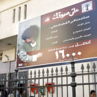 Egyptian children walk under a billboard that is part of a national campaign to encourage families to stop circumcising their daughters, outside the train station in the Upper Egyptian city of Minya in 2007. A 12-year-old girl died this week in southern Egypt after her parents brought her to a doctor who performed female genital mutilation, a criminal practice that remains widespread in the region, according to a judicial statement. The girl\'s death prompted Egypt\'s public prosecutor to order the arrests of her parents and the physician who preformed the procedure, also known as female circumcision, said the statement released late Thursday. | AP