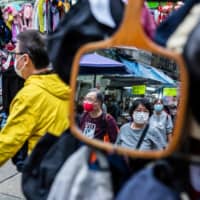 People wearing protective face masks walk through a market in Hong Kong on Tuesday. | AFP-JIJI
