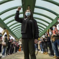 Winnie Yu, chairwoman of the Hospital Authority Employees Alliance, leads a protest demanding the government shut all entry points from China amid the deadly new virus outbreak outside Queen Mary Hospital in Hong Kong on Monday. | BLOOMBERG